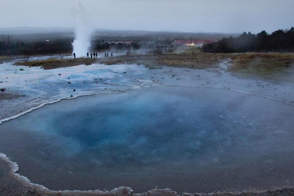 Au premier plan le bassin d'eau bleue "Blesi", qui réfléchit les paillettes de silice. Au second plan, le geyser Strokkur en éruption !